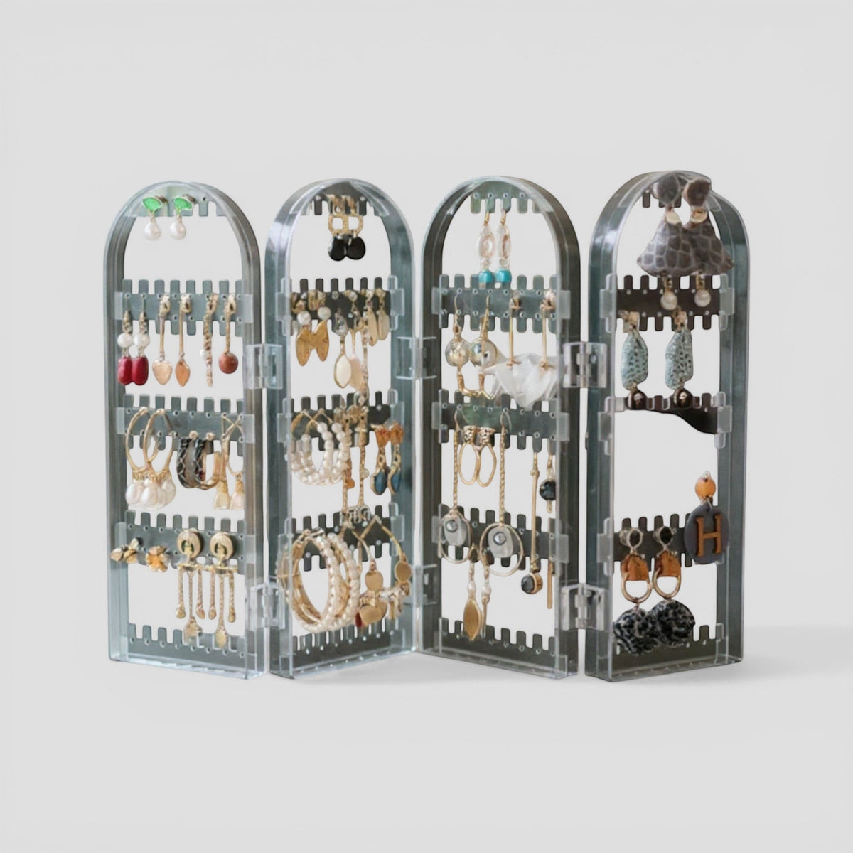 Présentoir à bijoux en acrylique transparent, avec plusieurs niveaux et compartiments pour organiser boucles d’oreilles et colliers.