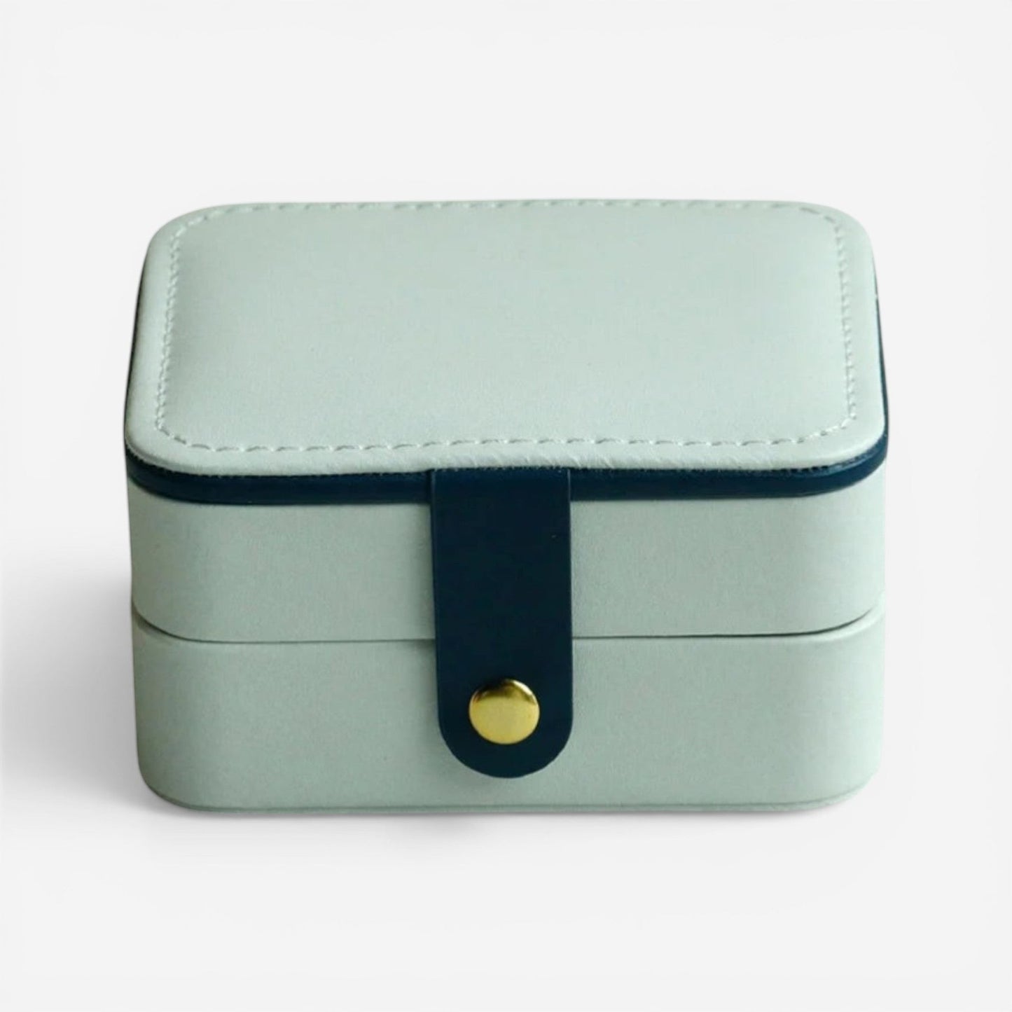 Boîte à bijoux blanche, fermée avec bouton doré dans un style minimaliste.