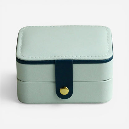 Boîte à bijoux blanche, fermée avec bouton doré dans un style minimaliste.