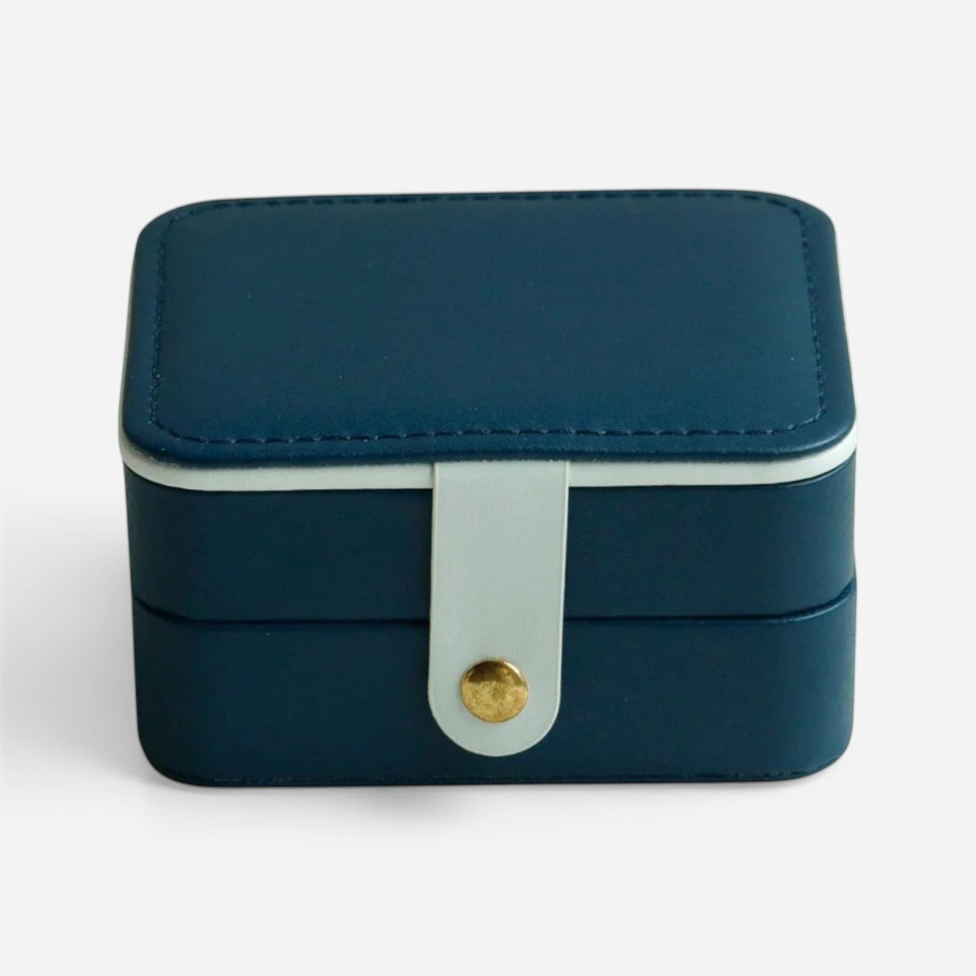 Boîte à bijoux bleu marine, fermée avec bouton doré et design compact élégant.