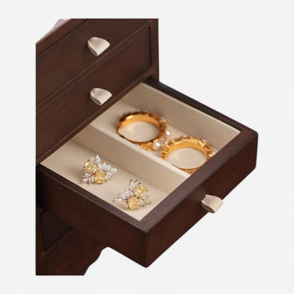 Détail d’un tiroir de boîte à bijoux en bois avec compartiments pour bagues et accessoires.