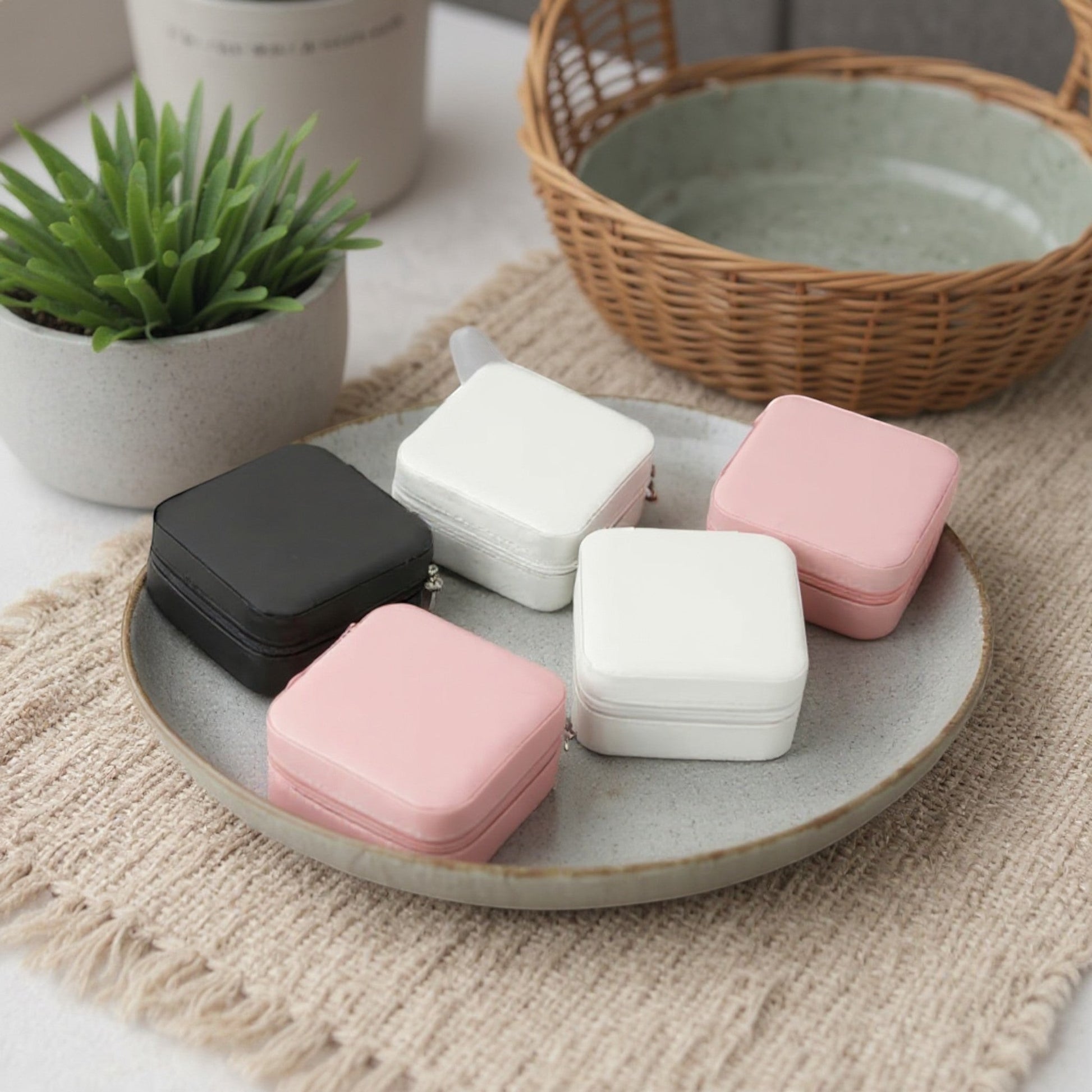Boîtes à bijoux carrées en velours, posées sur un plateau avec un intérieur décoratif et un style minimaliste.