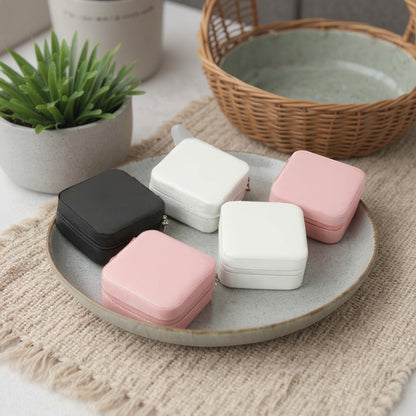 Boîtes à bijoux carrées en velours, posées sur un plateau avec un intérieur décoratif et un style minimaliste.