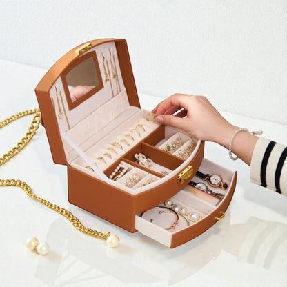 Boîte à bijoux compacte marron avec tiroir, miroir et compartiments pour bagues et colliers.