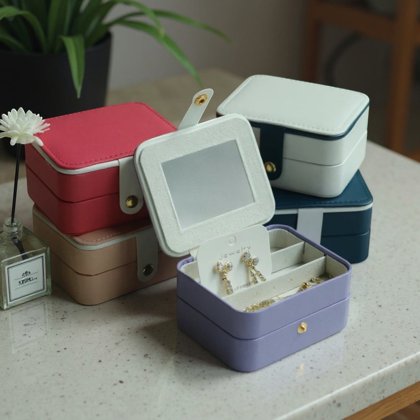 Boîtes à bijoux compactes de différentes couleurs, empilées sur une table dans un intérieur moderne et élégant.