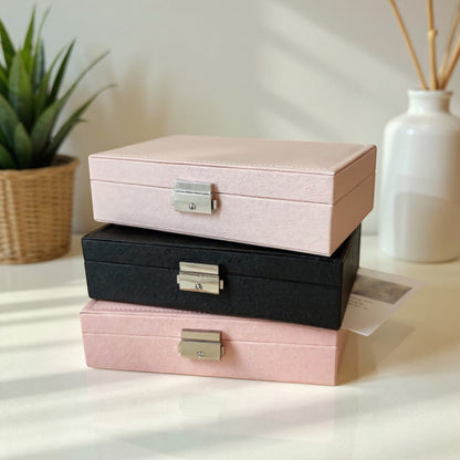 Boîtes à bijoux empilables en rose et noir avec design élégant et compact.