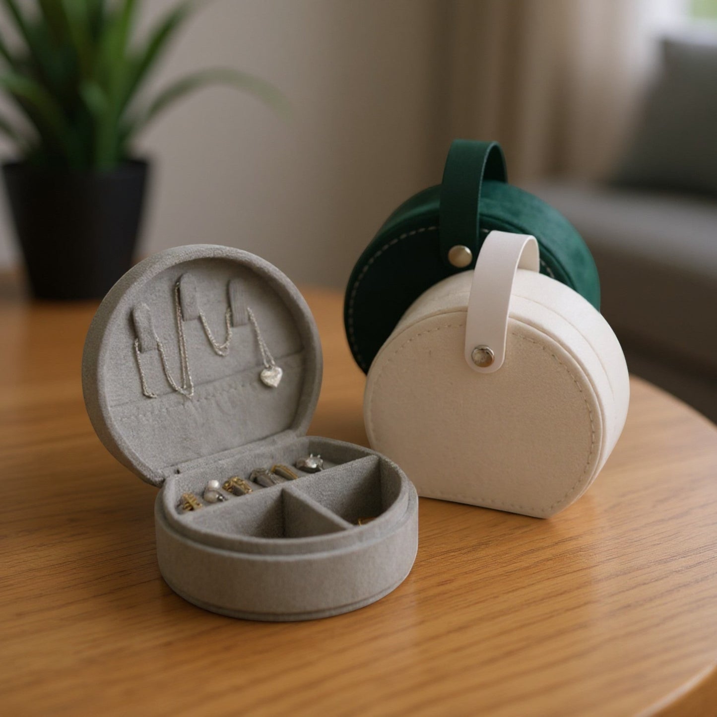 Boîte à bijoux en flanelle grise avec compartiments pour bagues et colliers, avec modèles crème et vert en arrière-plan.