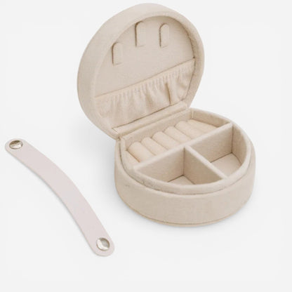 Boîte à bijoux ronde en flanelle beige ouverte avec compartiments pour bagues et accessoires.
