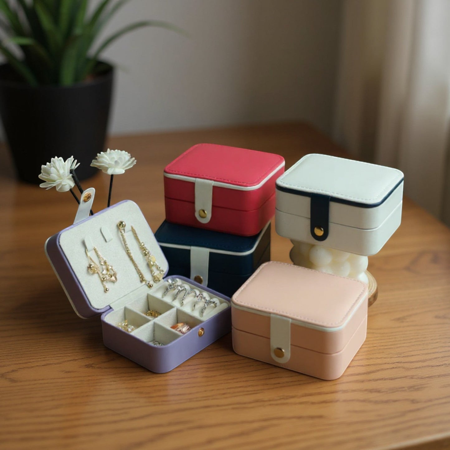 Boîte à bijoux ouverte avec compartiments, entourée de coffrets colorés sur une table en bois.