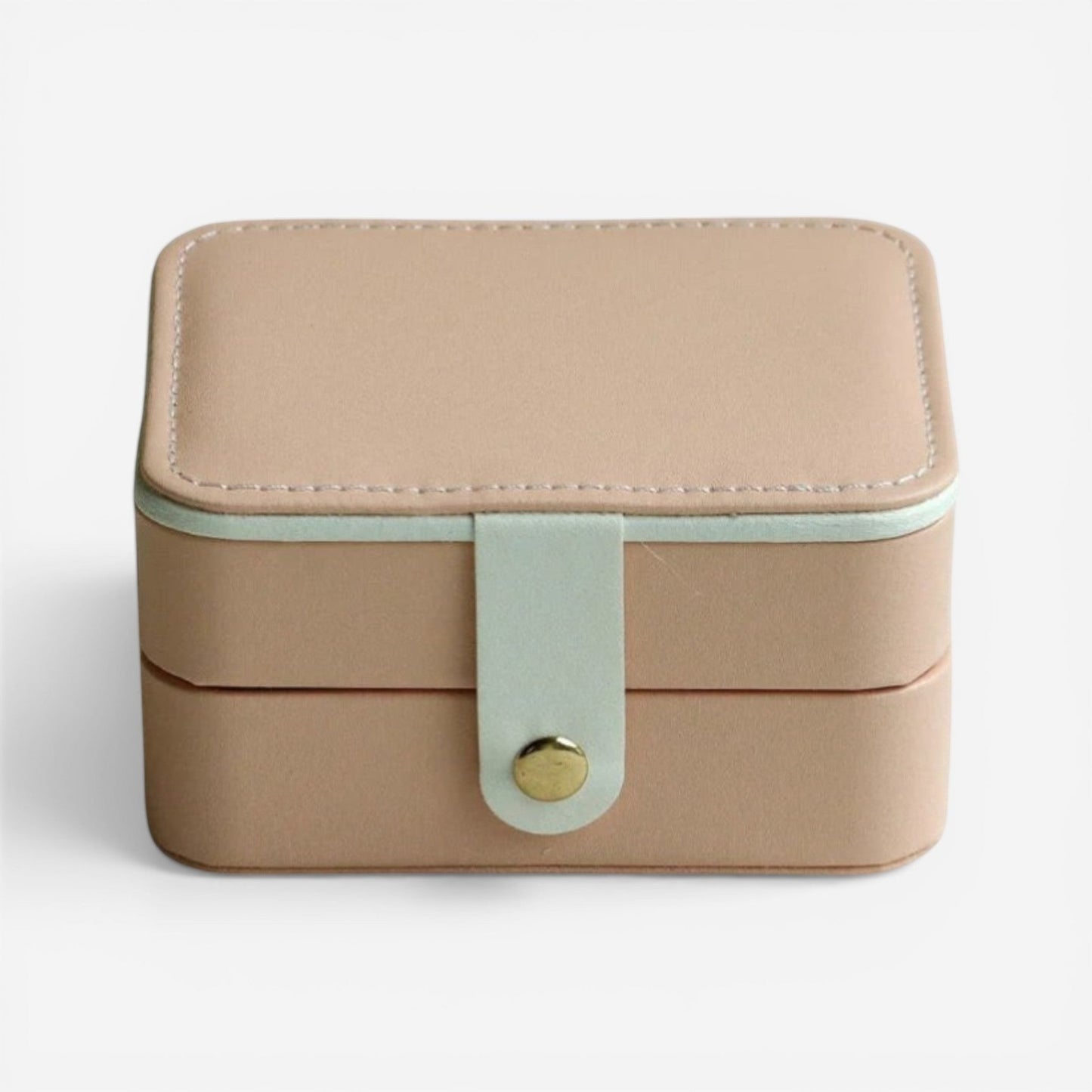 Boîte à bijoux rose, fermée avec bouton doré et design compact.