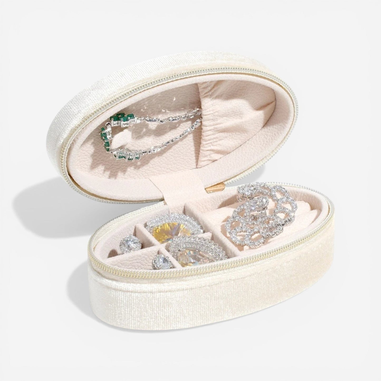 Boîte à bijoux ovale en velours beige, ouverte dans un style minimaliste avec rangement de bijoux.
