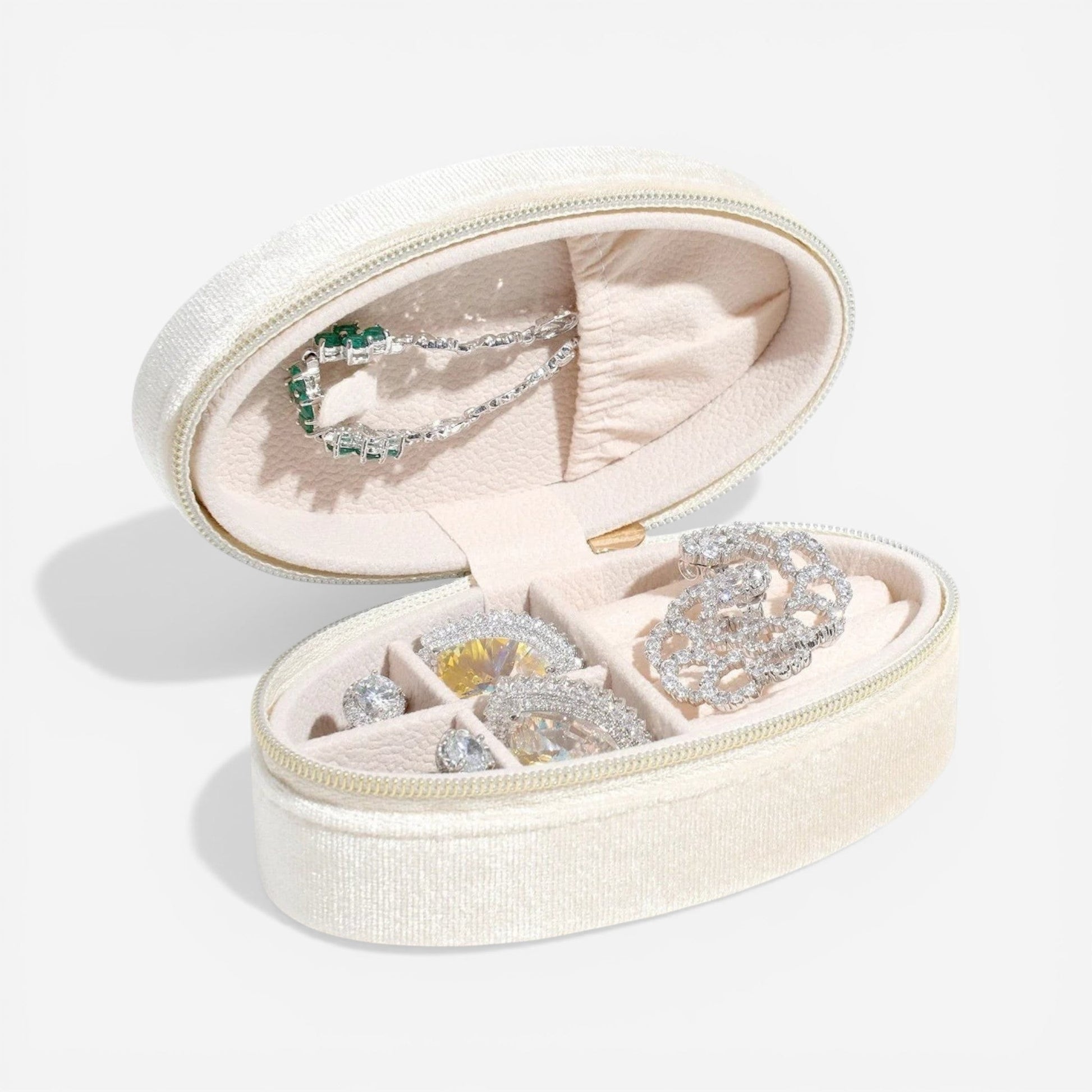 Boîte à bijoux ovale en velours beige, ouverte dans un style minimaliste avec rangement de bijoux.