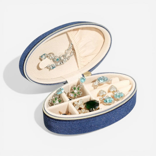 Boîte à bijoux ovale en velours bleu marine, ouverte avec des bijoux précieux bien organisés.
