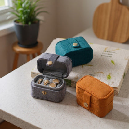Boîtes à bijoux en velours de différentes couleurs, posées sur une table dans un intérieur moderne.