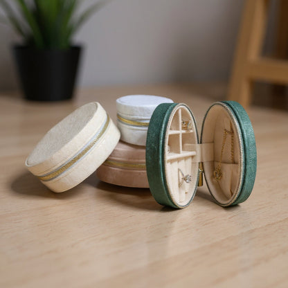 Boites a bijoux ovales en velours, fermées et posées sur une table, avec un design minimaliste.