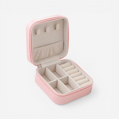 Boîte à bijoux carrée en velours rose, ouverte avec compartiments pour bagues et accessoires.