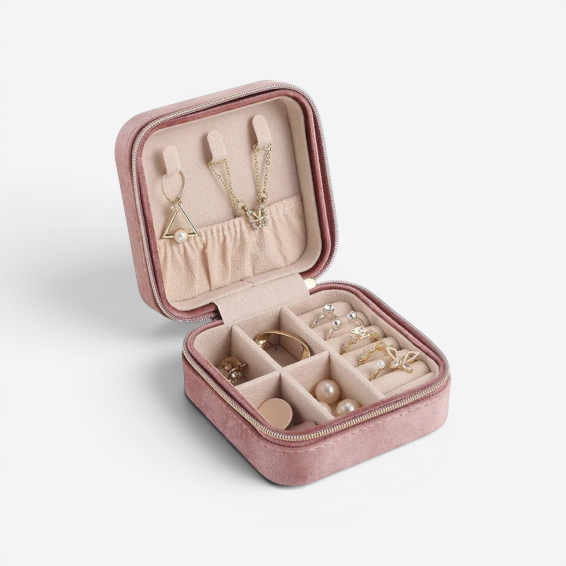 Boîte à bijoux en velours rose, ouverte avec compartiments pour bagues et colliers.