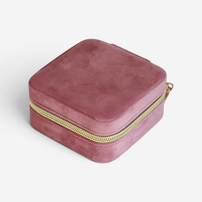 Boîte à bijoux en velours rose foncé, fermée avec fermeture éclair et design compact.
