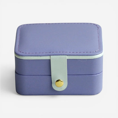 Boîte à bijoux violette, fermée avec bouton doré et finition douce.