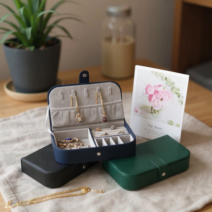 Boîte à bijoux portable en cuir PU bleu marine avec fermeture à bouton, comprenant des emplacements pour bagues et colliers.