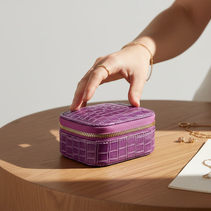 boite à bijoux de voyage violette en cuir effet crocodile tenue en main avec fermeture éclair et rangement intérieur