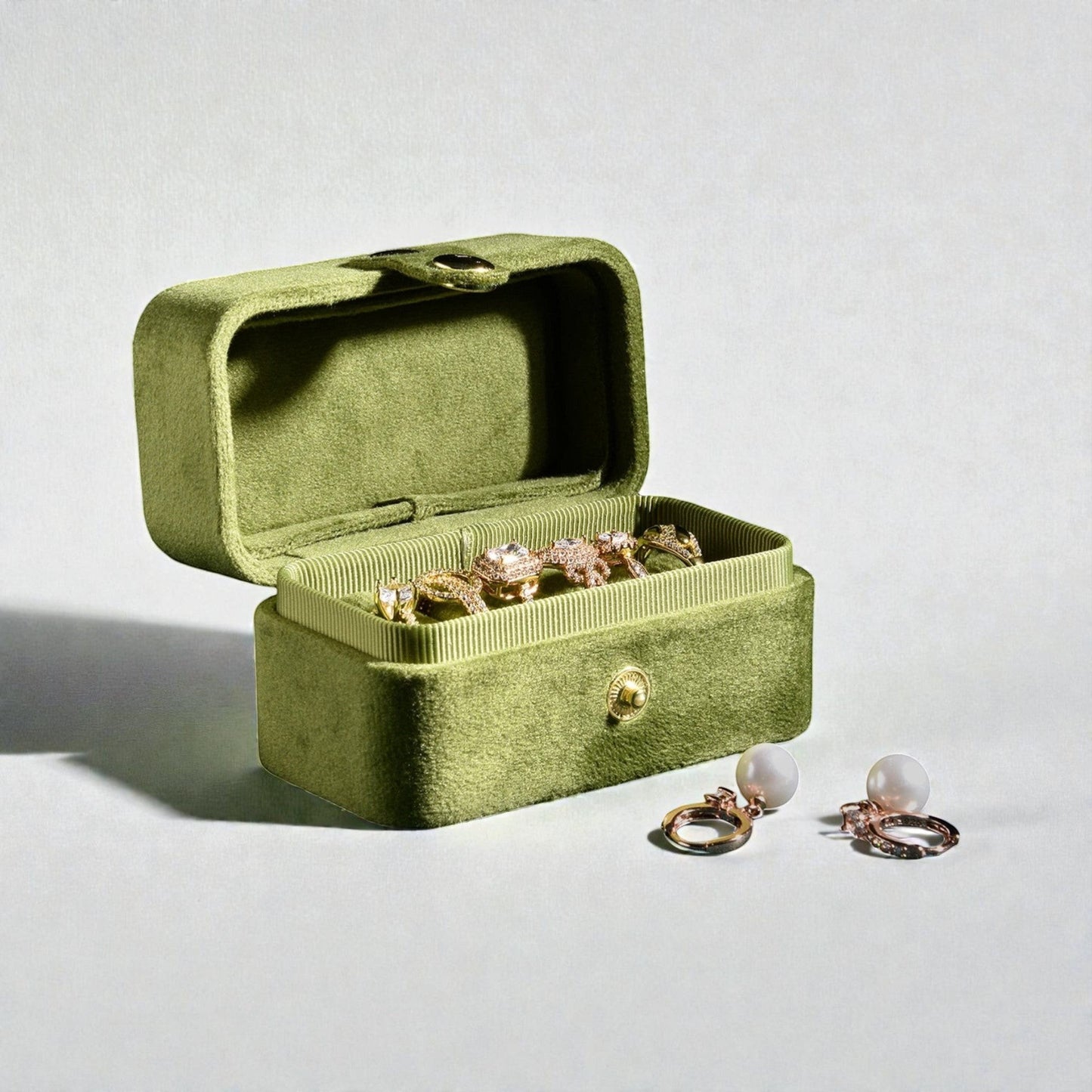 Boîte à bijoux de voyage en velours vert, ouverte, montrant les compartiments pour bagues et accessoires.