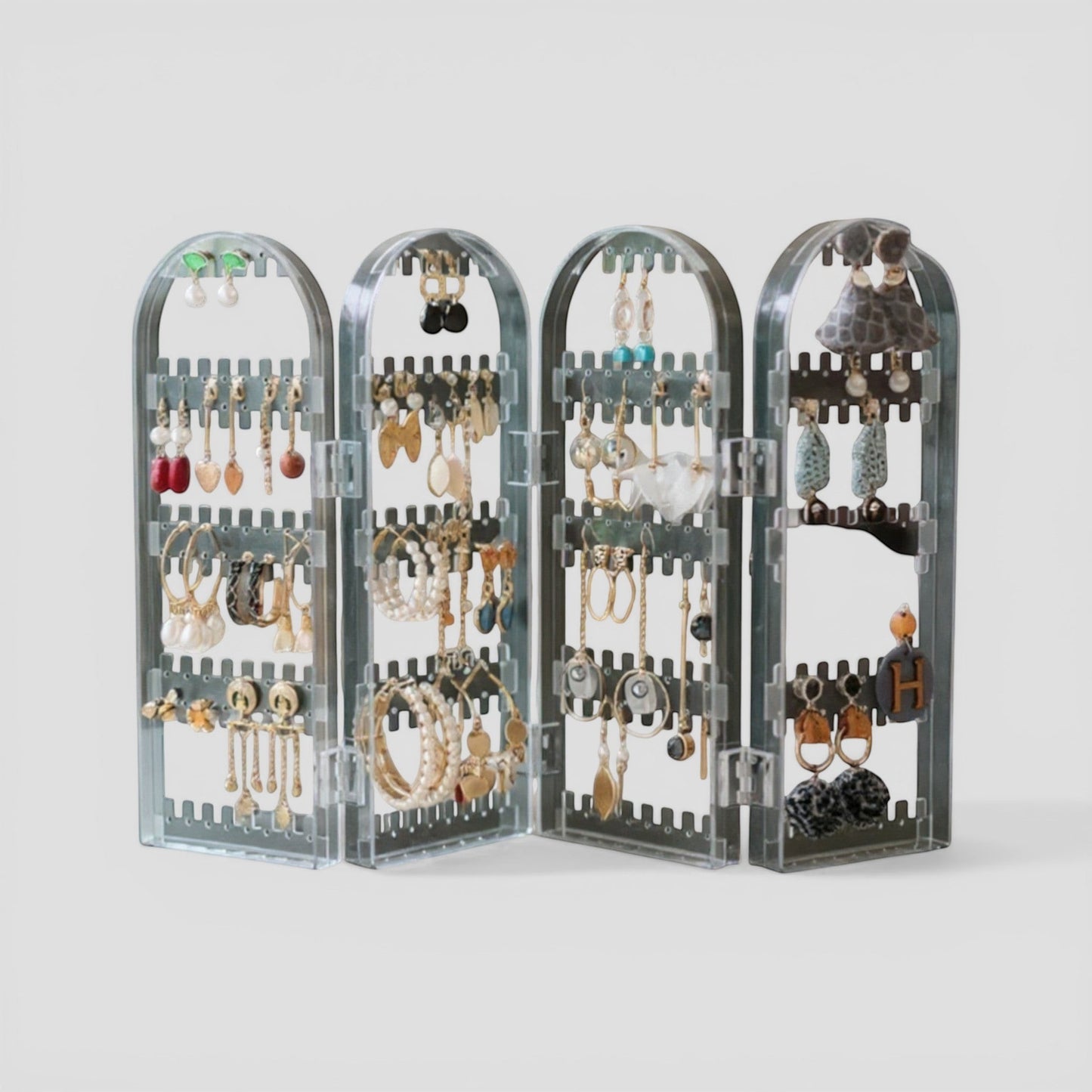 Présentoir à bijoux en acrylique transparent, avec plusieurs niveaux et compartiments pour organiser boucles d’oreilles et colliers.