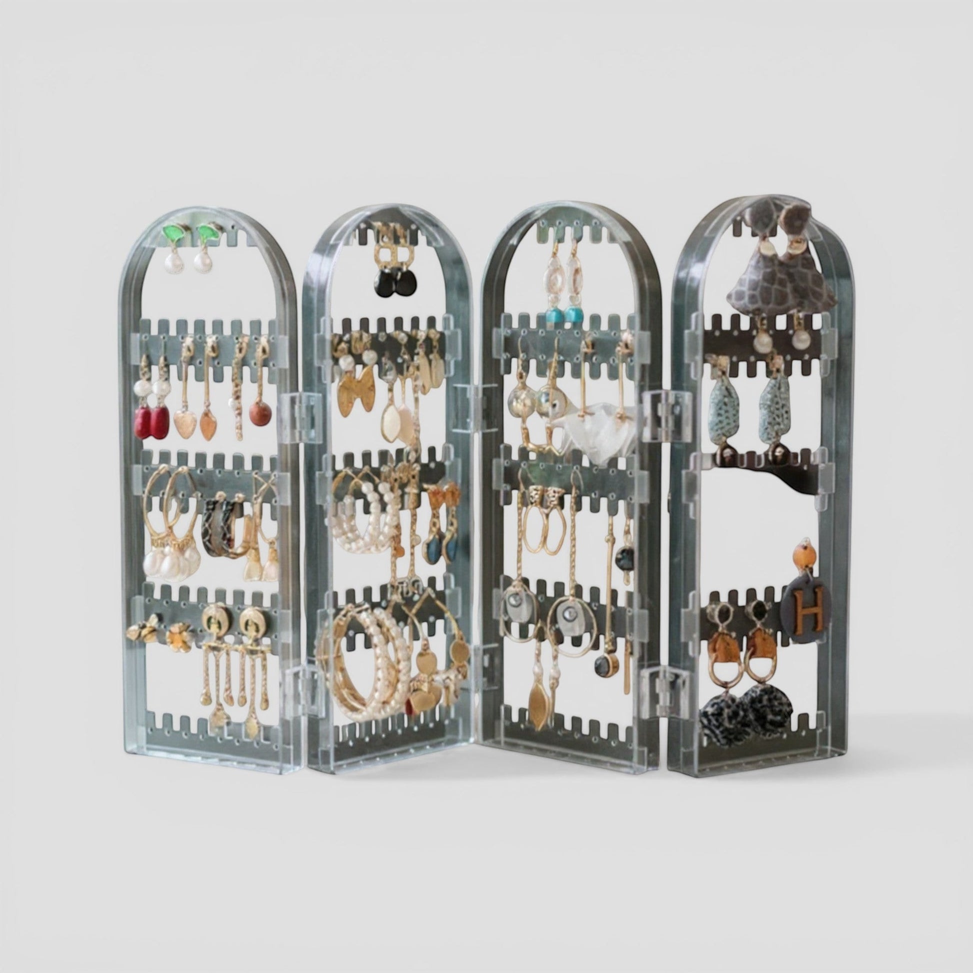 Présentoir à bijoux en acrylique transparent, avec plusieurs niveaux et compartiments pour organiser boucles d’oreilles et colliers.