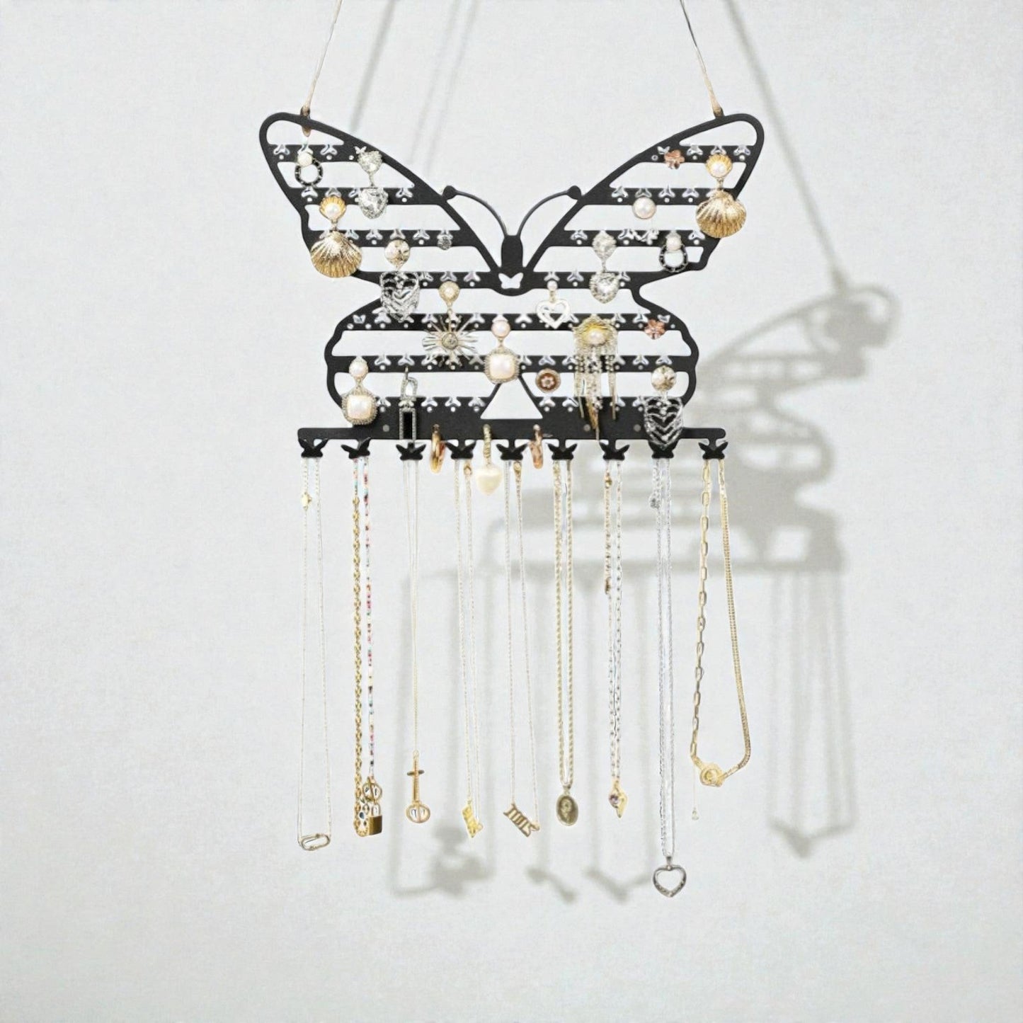 Présentoir à bijoux mural en forme de papillon noir avec colliers suspendus et rangement élégant.