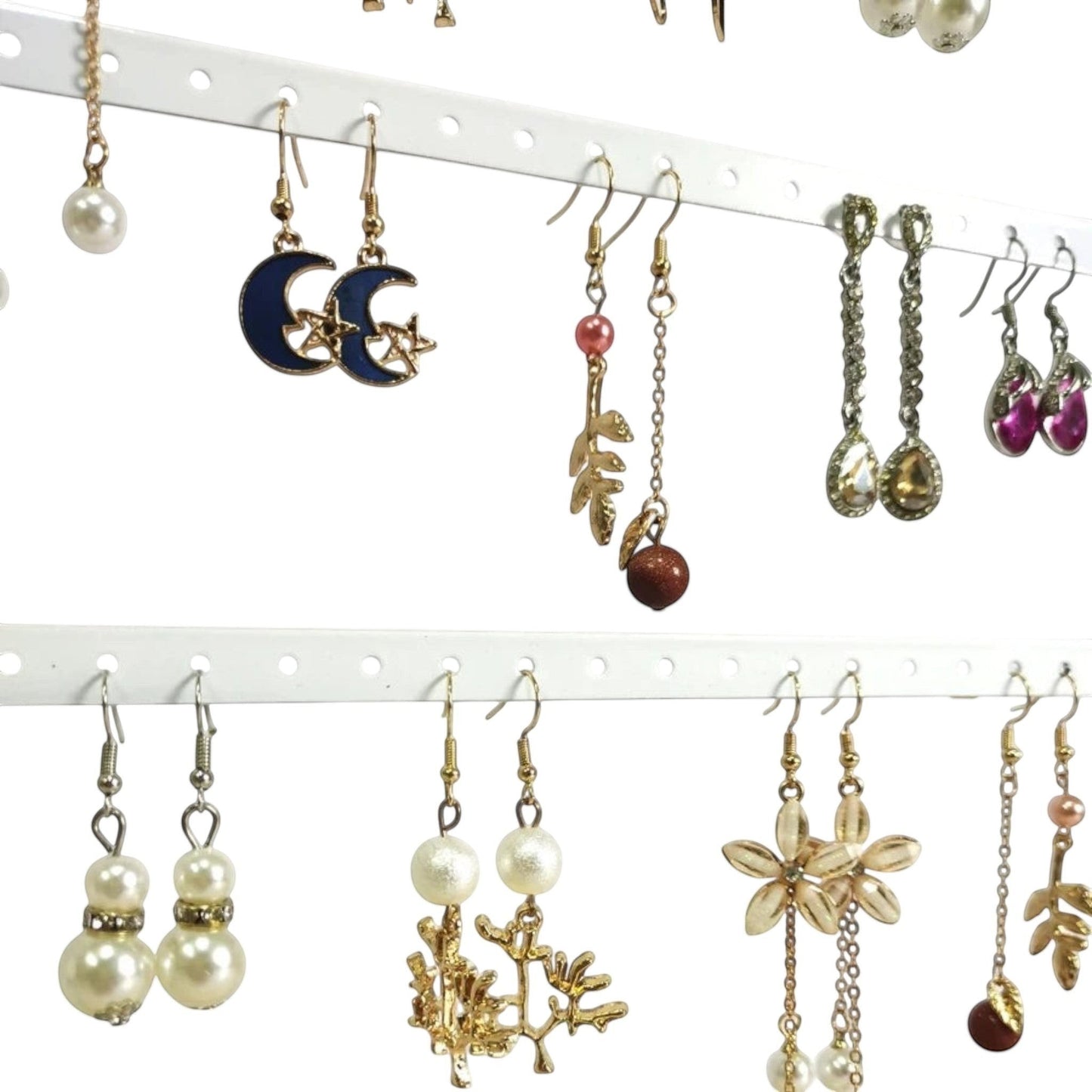 Détail de boucles d’oreilles suspendues sur un présentoir en métal avec plusieurs rangées de trous.