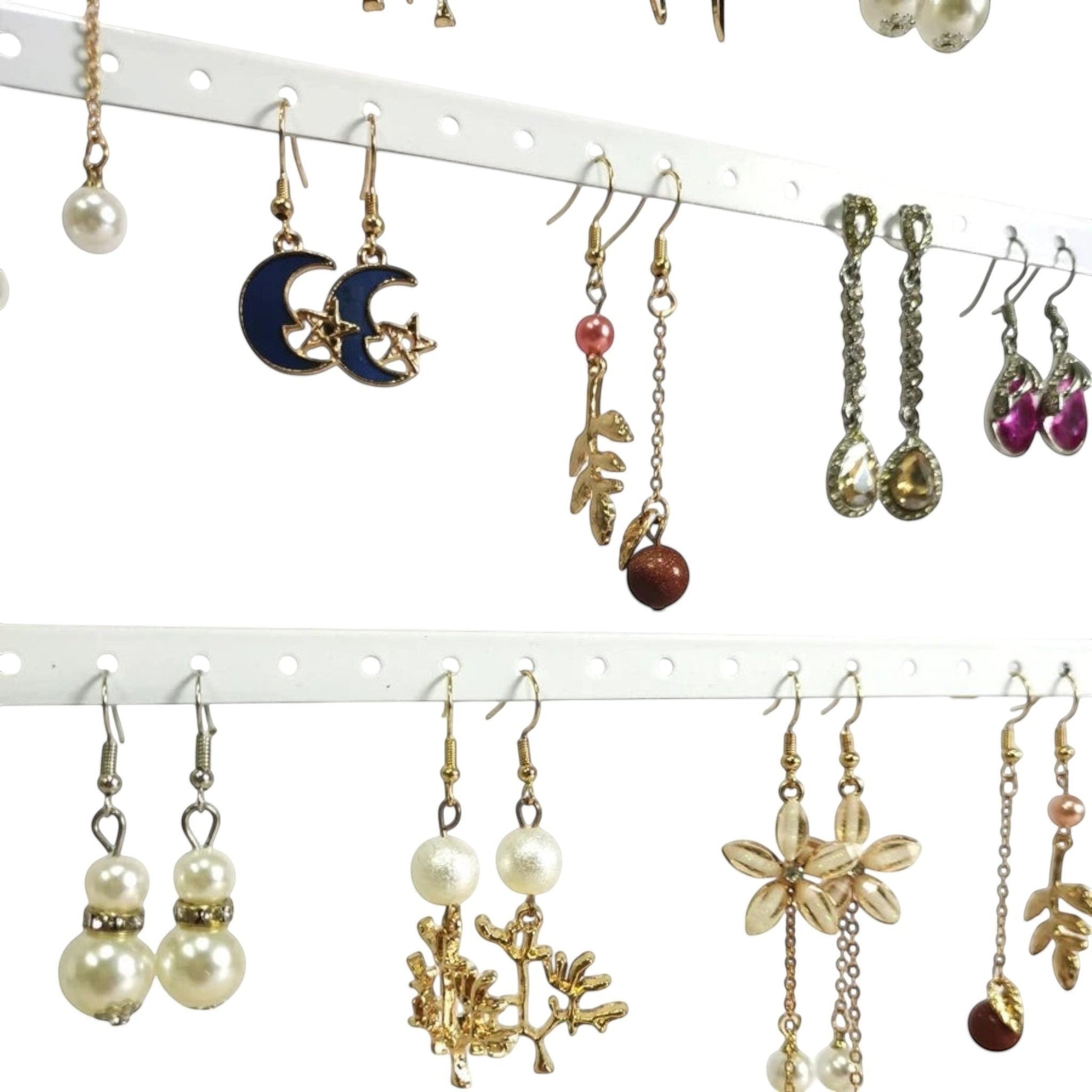Détail de boucles d’oreilles suspendues sur un présentoir en métal avec plusieurs rangées de trous.
