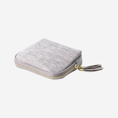 Sac de rangement pour bijoux en velours gris avec fermeture éclair et pompon décoratif.