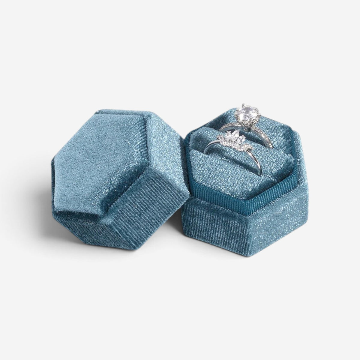 Boîte à bijoux hexagonale SecretGleam en velours bleu contenant deux bagues de fiançailles en argent