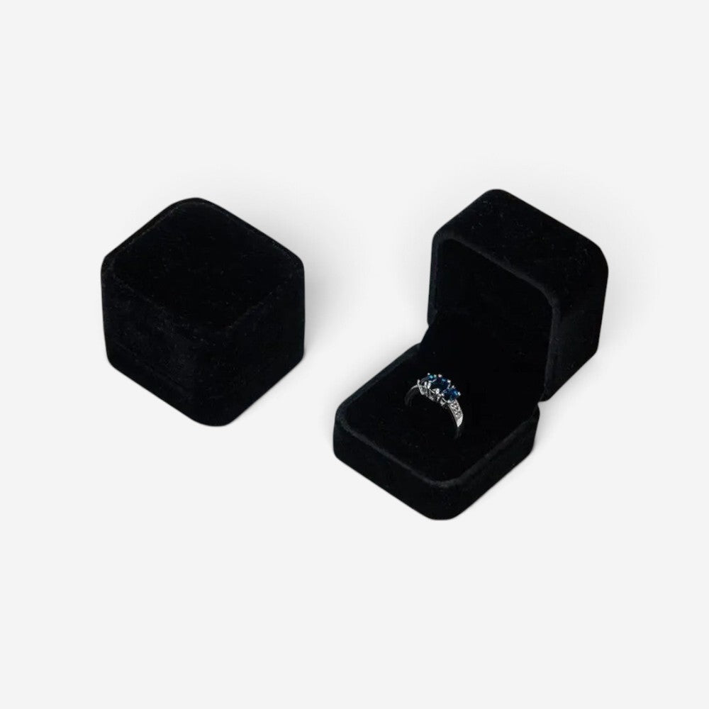 Boîte à bijoux carrée en velours noir SecretGleam avec une bague à pierres bleues à l'intérieur