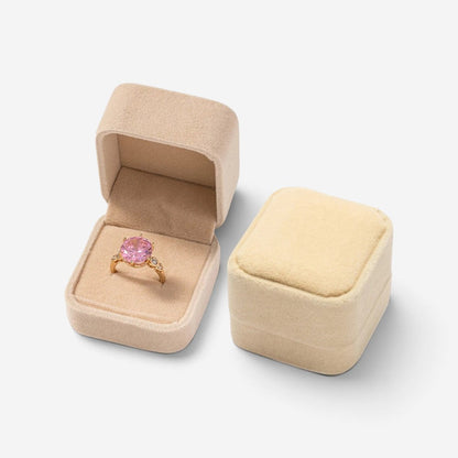 Mini boîte à bijoux SecretGleam en velours beige avec une bague à pierre rose, format compact pour bagues