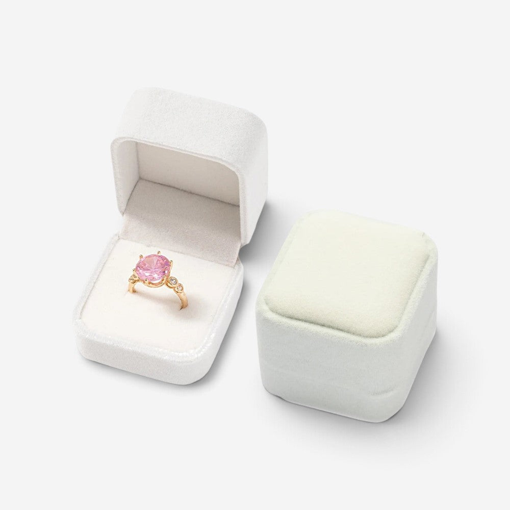 Mini boîte à bijoux SecretGleam en velours blanc, ouverte avec une bague à pierre rose et une boîte fermée à côté
