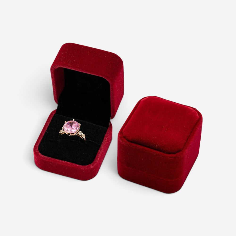 Mini boîte à bijoux SecretGleam en velours rouge avec une bague à pierre rose à l'intérieur